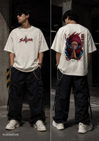 A model shown in a split front-and-back view wearing an off-white graphic t-shirt, black cargo pants, and white sneakers in a dark industrial setting. The front features a red and black 'SUKUNA' logo, and the back features a large colorful anime-style character graphic with red hair and blue accents.