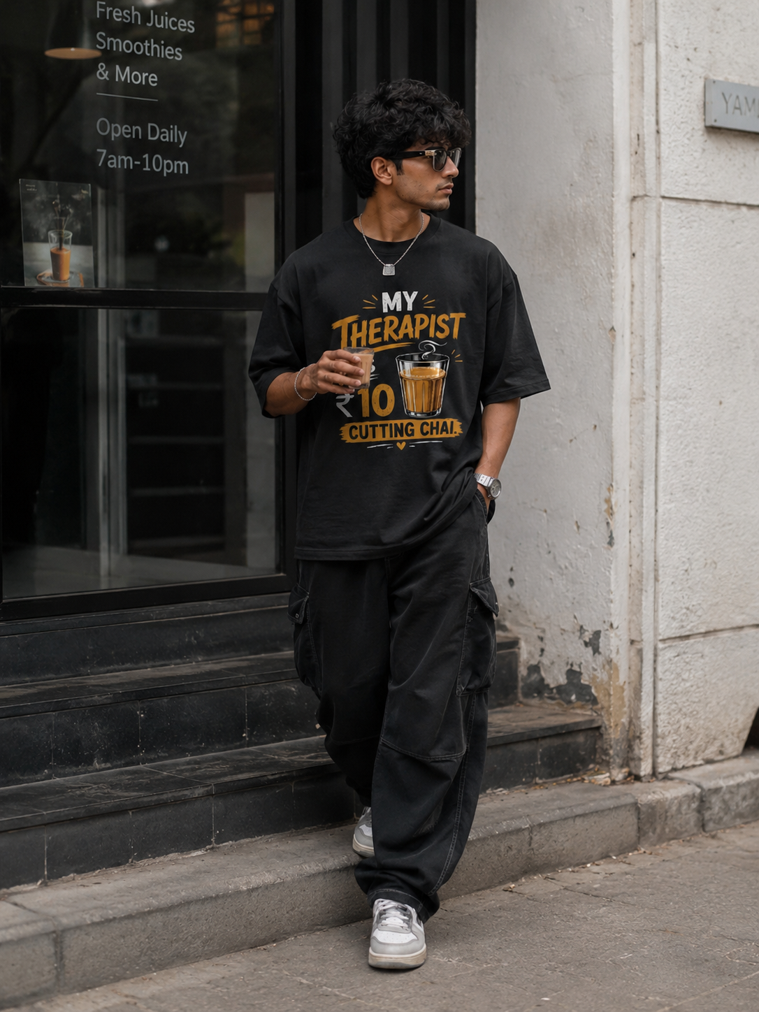 Person wearing a black t-shirt with humorous text design, standing outside a building.