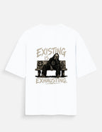 White oversized back print t-shirt featuring a tired man sitting on a couch with the quote "Existing Is Exhausting" in vintage grunge style by Kurowear.