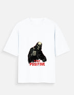 White t-shirt with a graphic of a skeleton holding a sign that says 'Stay Positive' on a white background.