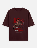 A dark maroon short-sleeve t-shirt with a graphic print of the anime character Jogo from Jujutsu Kaisen, featuring red Japanese kanji and text, displayed on a light gray background.