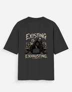 Black oversized back print t-shirt featuring a tired man sitting on a couch with the quote "Existing Is Exhausting" in vintage grunge style by Kurowear.