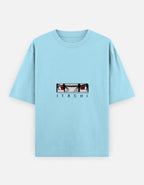 A light blue short-sleeve t-shirt featuring a graphic of Itachi Uchiha's eyes and the name 'ITACHI' printed on the chest, displayed against a light gray background.