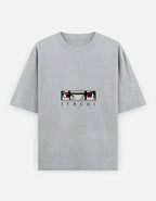 A light gray heather short-sleeve t-shirt featuring a graphic of the anime character Itachi Uchiha's eyes and the name 'ITACHI' printed below it, displayed on a clean white background.